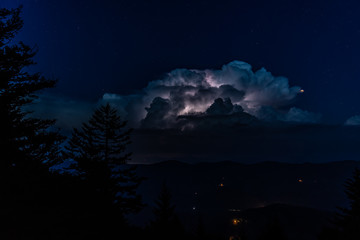 A huge thunderstorm with active lightning lighting up the clouds is seen from the high peak of Spruce Knob in the Appalachian Mountains of West Virginia