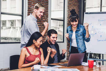Fototapeta premium Successful of group of casual business discussing and working with laptop computer.creative business people celebrating with arms up in modern workloft.Teamwork concept