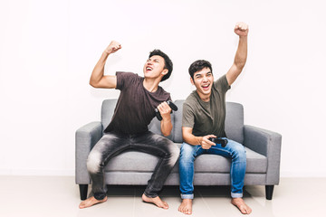 Two friends sitting on sofa and enjoying play video game together at home