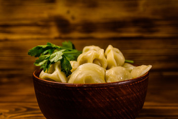 Fresh dumplings in ceramic bowl on wooden table