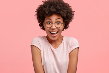 People and reaction concept. Happy overjoyed young African American female reacts on positive news,...
