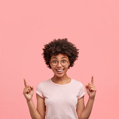 Vertical portrait of positive cheerful African American female with friendly smile, dressed in...