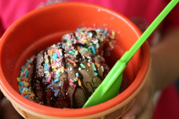 chocolate ice cream with topping on top served in a small plastic cup