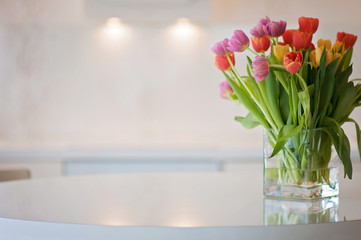 A white and clean home office kitchen background with colorful tulip flowers in front. Typical Scandinavian/Nordic interior in Finland.