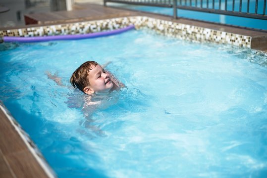 Little boy swiming in pool in summer holidays 