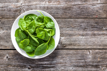 Healthy spinach, plate with leafy green vegetables on wooden table. Fresh organic food and...
