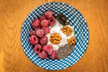 healthy fitness breakfast with berries, nuts, grains, yogurt and oil in a bowl