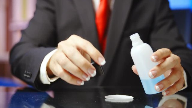 Man with french manicure removing polish from nails 4K. Static medium shot of headless male person hands in focus while opening an acetone bottle and wiping away white nails. Wearing blue shirt.