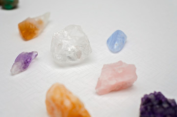 Healing crystals on a white table including: Amethyst Point and Cluster, Clear Quartz, Citrine, Calcite and Rose quartz. Gemstones are full of healing energy and good vibes.