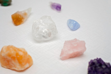 Healing crystals on a white table including: Amethyst Point and Cluster, Clear Quartz, Citrine, Calcite and Rose quartz. Gemstones are full of healing energy and good vibes.