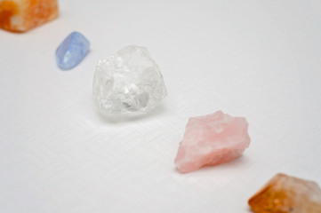 Healing crystals on a white table including: Clear Quartz, Citrine, Calcite and Rose quartz....
