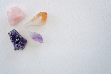Healing crystals on a white table including: Amethyst Point and Cluster, Citrine and Rose quartz. Gemstones are full of healing energy and good vibes.