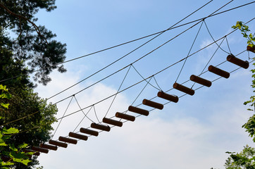 Rope bridge with wooden ladder in adventure park
