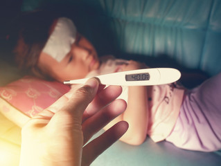 Hand holding thermometer with high fever temperature on blurred child sick on background