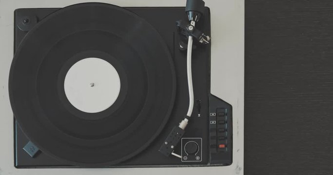 The male hand removes the needle from the vinyl record and stops the player.