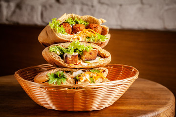 Concept of vegetarian food. pita with falafel, salad, vegetables, tofu cheese in a wicker basket on...