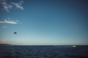 Parachute over the sea against a blue sky and clear sea water, towing on a boat. Riding a parachute behind a boat. The concept of travel, release, summer, rest