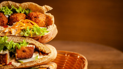 Concept of vegetarian food. pita with falafel, salad, vegetables, tofu cheese in a wicker basket on...