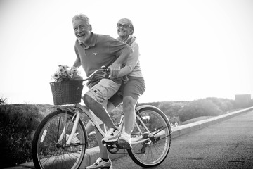 joy and happiness for adult married couple start and have fun traveling on the same bike in outdoor activity with sun backlight on the background. clear and bright image for smile and laugh people..