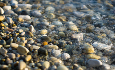 pebble stones on the sea beach, the rolling waves of the sea with foam