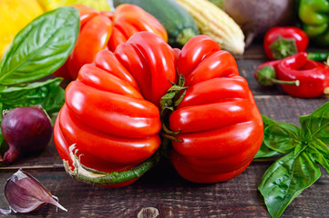 A large ripe red tomato with basil on a wooden table. Italian tomato variety.
