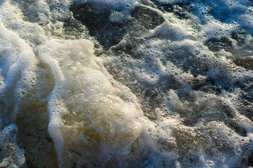 pebble stones on the sea beach, the rolling waves of the sea with foam