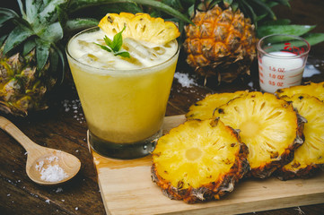 Pineapple juice and pineapple slices cut into pieces on a wooden table. Healthy wood fiber helps to...