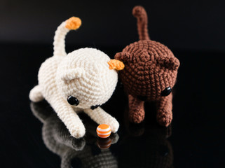 Toy kittens play with a ball,  black background