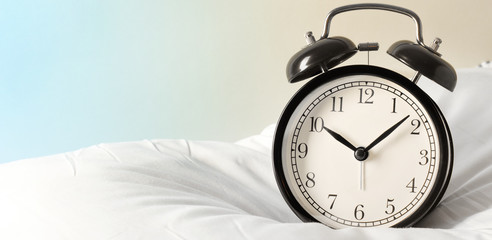 Alarm clock on the pillows. Advertising concept, copy space