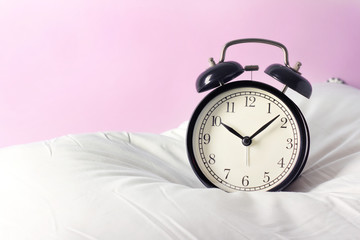 Alarm clock on the pillows. Advertising concept, copy space