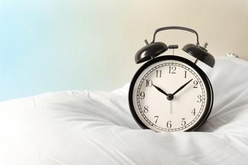 Alarm clock on the pillows. Advertising concept, copy space