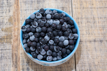 White bowl full with frozen aronia berries