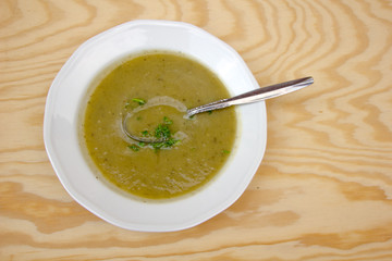 Delicious green zucchini soup with zucchini on a wooden table with a spoon and soup bowl