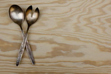 Two metallic silverware spoon and fork for salads placed on a dark marble surface, ideal for backgrounds with edited textual content for restaurants or food or menus or also recipe display