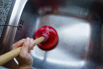 A red suction cup placed on the outflow of a metallic kitchen sink to get the dirt out of the...