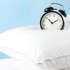 Alarm clock on the pillows. Advertising concept, copy space