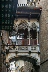 A medieval bridge between building on the quiet narrow streets in the Gothic quarter of Barcelona in the morning - 1