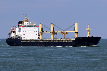Fototapeta premium Massengutfrachter mit Kränen läuft im Hafen ein