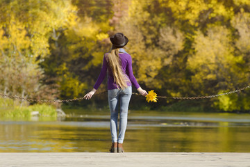 Fototapeta na wymiar Girl in hat standing on the dock. Autumn sunny day. Back view