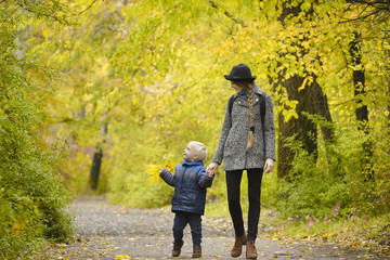 Obraz premium Mom and son are walking in the autumn forest.