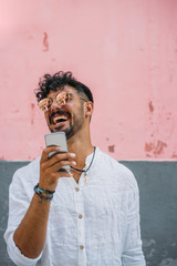 Outdoor portrait of handsome young hipster man with mobile phone.