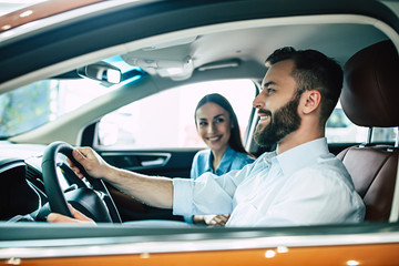 Husband and wife. Happy young couple chooses and buying a new car for the family in the dealership.