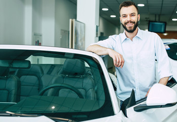 Succsess handsome bearded man buying a new sport car in dealership