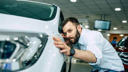 Serious handsome bearded man buying a car in dealership