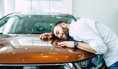 Dreams come true today. Happy handsome bearded man buying a car in dealership