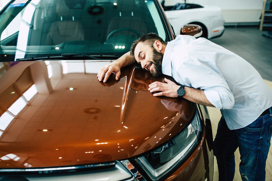 My dream. Happy handsome bearded man buying a car in dealership