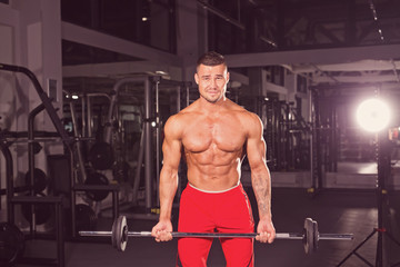 Muscular young man lifting weights in gym