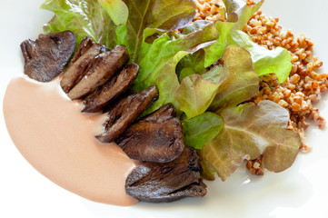 fried slices of turkey hearts in red wine sauce garnished with buckwheat porrige and latuce leafs