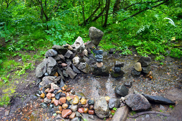 The unusual shape of the stones. Stone tower against the forest. River stone. Stream in the forest.