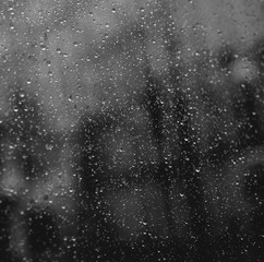 Naklejka na ściany i meble Square closeup of raindrops on window glass. Blurred office lights on background.